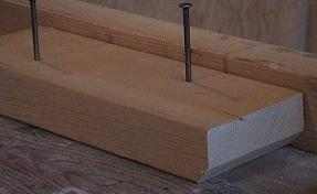 Photo of circular skil saw stop block partially nailed onto bench.