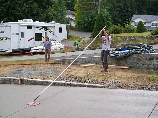 Photo of worker using the concrete float to smooth the surface of the concrete driveway.